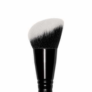 A makeup brush with a black handle and dual-toned bristles that transition from white to black, shown against a plain white background.
