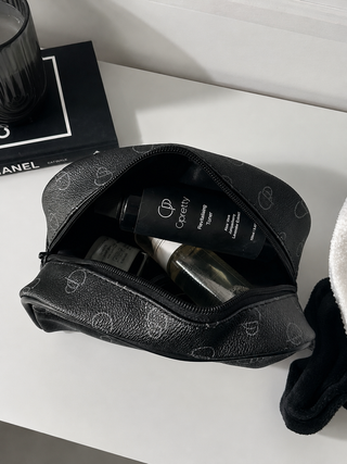 Black toiletry bag with cosmetic items on a white surface