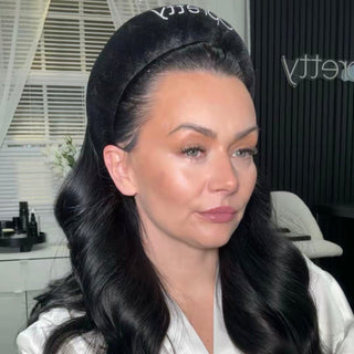 Woman with black hair wearing a headband in a room with a window and chair.