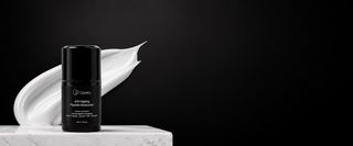 A black cosmetic bottle labeled opretty Anti-Aging Retinol Night Moisturizer' stands on a white marble pedestal next to a white cream smear against a solid black background.